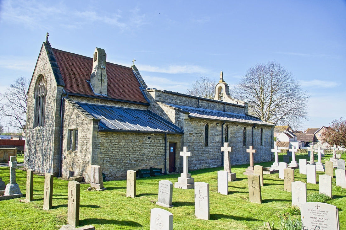 Stone church with a cemetery featuring gravestones under a clear blue sky.