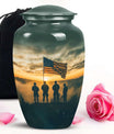 Cremation urn with American flag and soldiers design, accompanied by a pink rose and black bag.