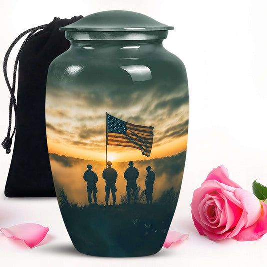 Cremation urn with American flag and soldiers design, accompanied by a pink rose and black bag.