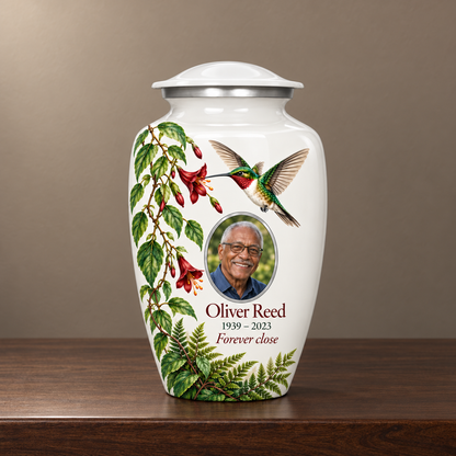 White hummingbird adult urn with Oliver Reed sample photo and text displayed on a memorial console
