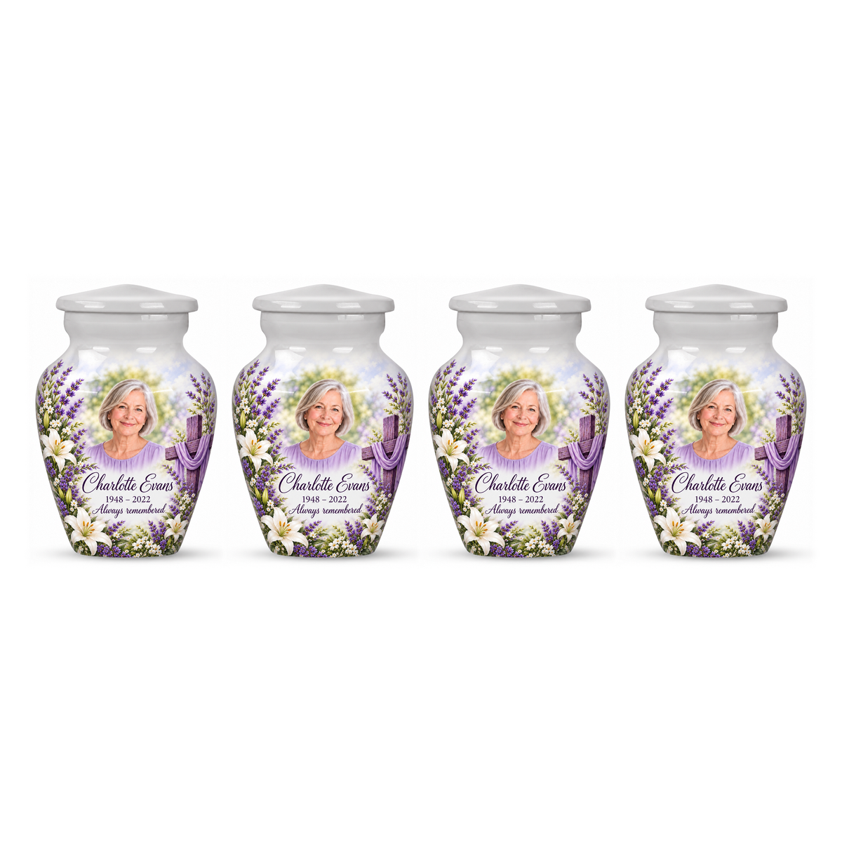 Four matching white cross keepsake urns with white lilies and lavender arranged on white.