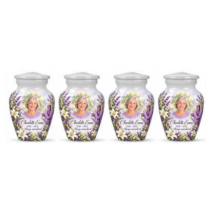 Four matching white cross keepsake urns with white lilies and lavender arranged on white.