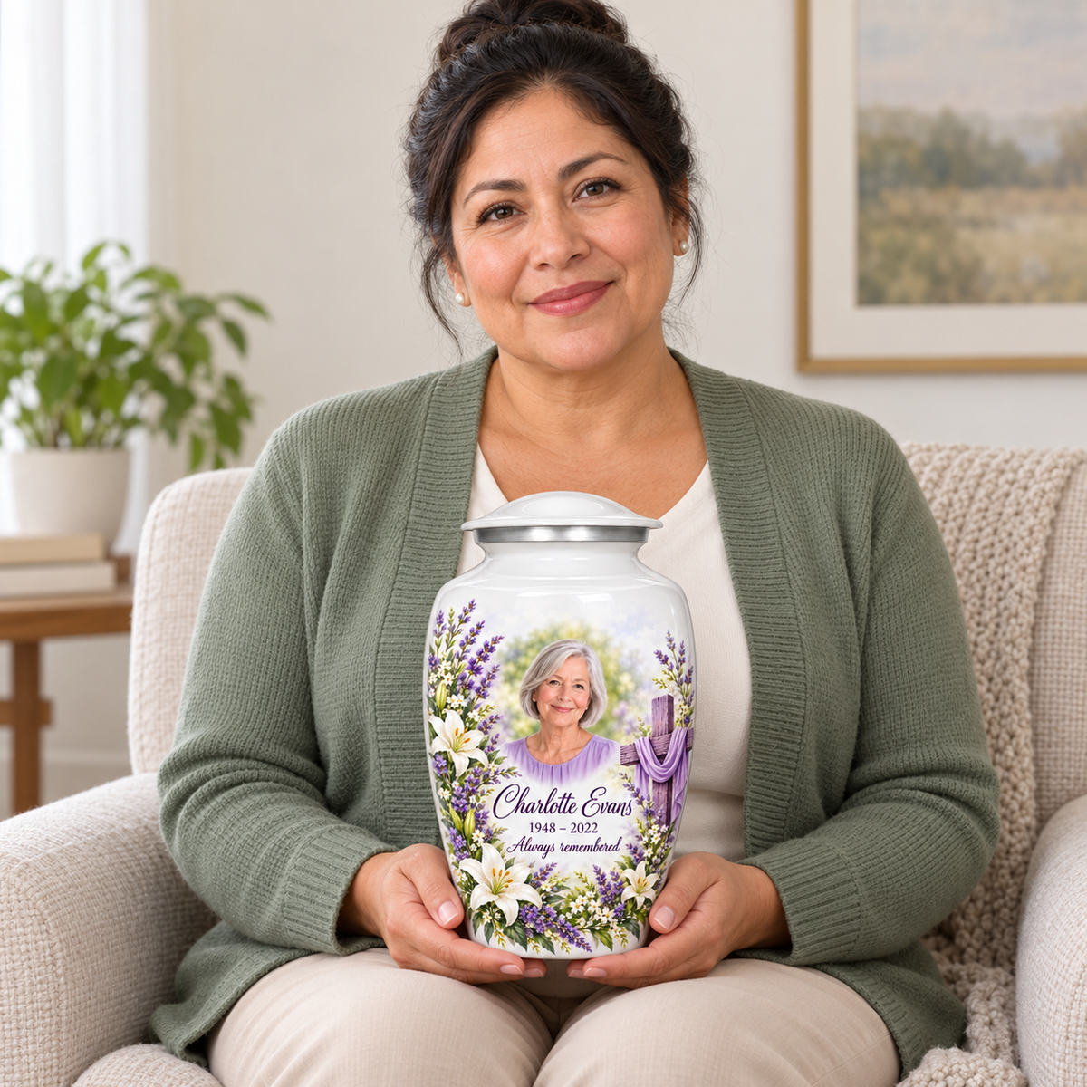 A seated person holding the white cross urn with white lilies and lavender on their lap.