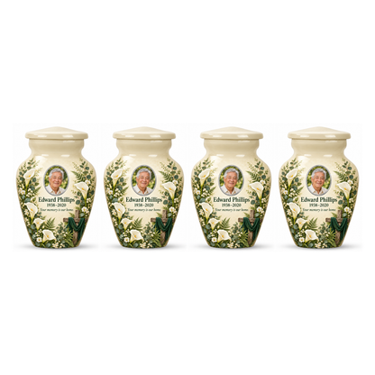 Four matching white cross keepsake urns with white calla lilies and greenery arranged on white.