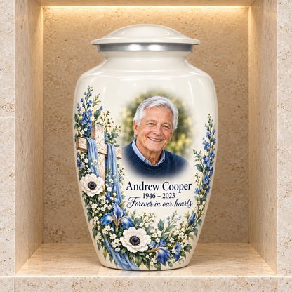 White adult cross urn with blue and white flowers displayed in a stone columbarium niche.
