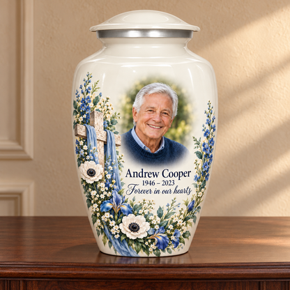 White adult cross urn with blue and white flowers displayed on a memorial console.