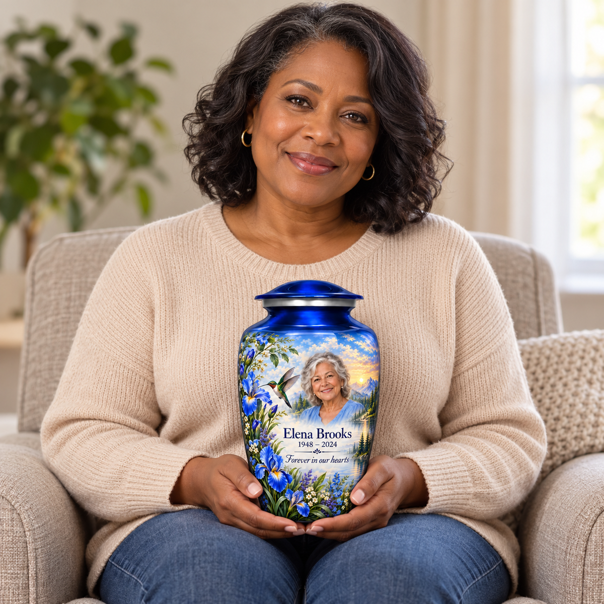 A seated person holding the blue hummingbird adult urn with irises and Elena Brooks sample photo and text on their lap