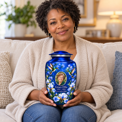 A seated person holding the blue hummingbird adult urn with Grace Ellis sample photo and text
