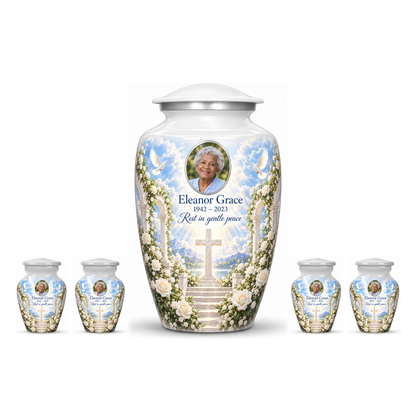 One white adult cross urn and four keepsakes with white roses and garden steps arranged on white.