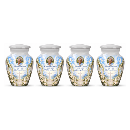 Four matching white cross keepsake urns with white roses and garden steps arranged on white.