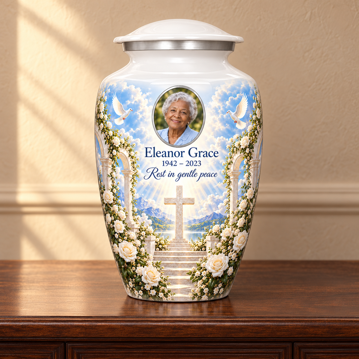 White adult cross urn with white roses and garden steps displayed on a memorial console.