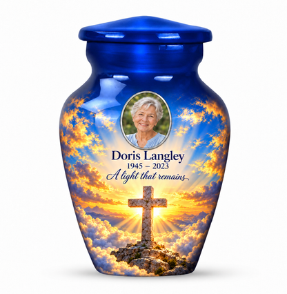 One blue cross keepsake urn with golden sunlight and clouds, sample portrait and tribute on white.
