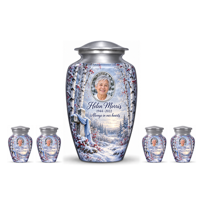 One silver adult cross urn and four keepsakes with snowy birches and red berries arranged on white.