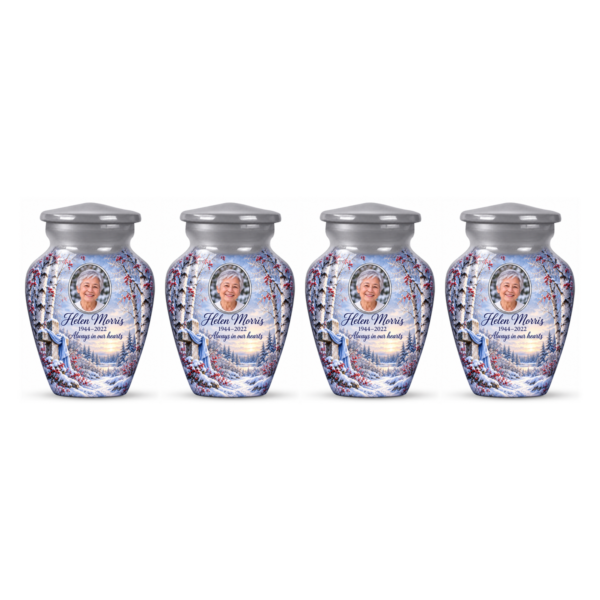 Four matching silver cross keepsake urns with snowy birches and red berries arranged on white.