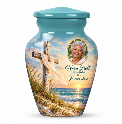 One green cross keepsake urn with sandy dunes and sea, sample portrait and tribute on white.