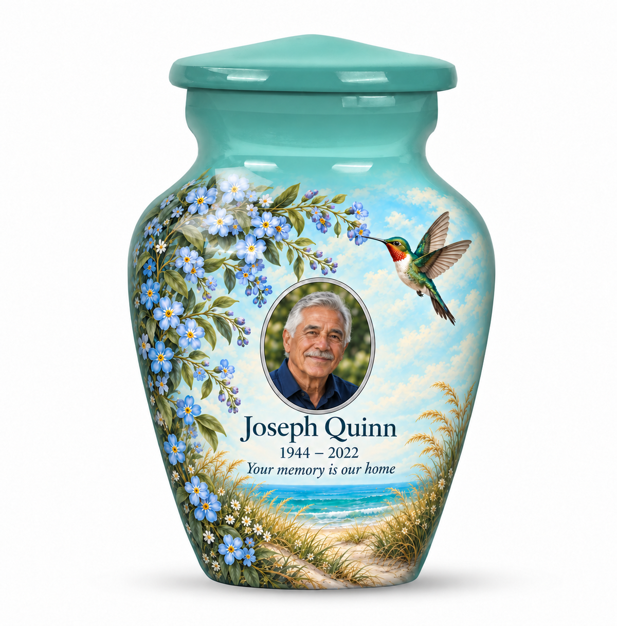 One seafoam green hummingbird keepsake urn with blue forget-me-nots and a coastal scene, Joseph Quinn sample portrait and memorial text on white.