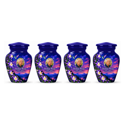 Four matching indigo blue hummingbird keepsake urns in a row on white, each with Thomas Wynn sample portrait and memorial text.