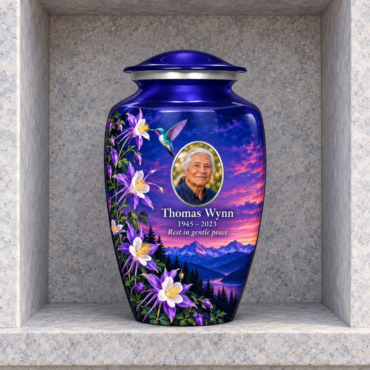 Indigo blue hummingbird adult urn with Thomas Wynn sample portrait and memorial text in a stone columbarium niche.