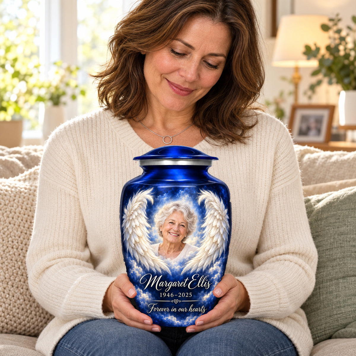 Seated person holding the blue Midnight Embrace adult urn with sample portrait and inscription on their lap.