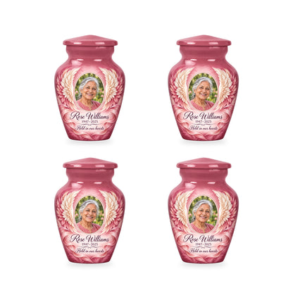 Four matching pink angel wings keepsake urns with sample photo and inscription.
