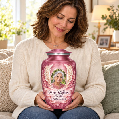 Seated person holding the pink adult angel wings urn on their lap.
