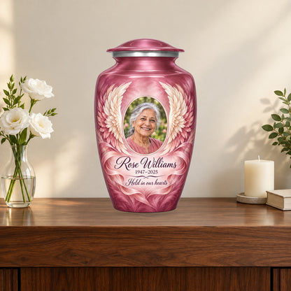 pink personalized angel wings adult urn on a memorial console.