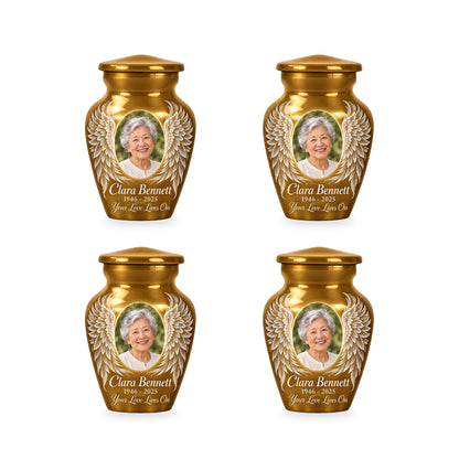Four matching gold angel wings keepsake urns with sample photo and inscription.