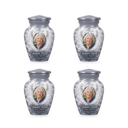 Four matching gray angel wings keepsake urns with sample photo and inscription.