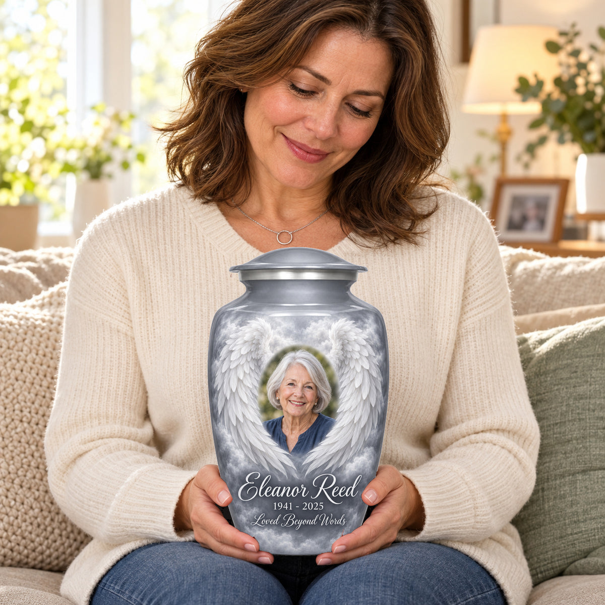 Seated person holding the gray adult angel wings urn on their lap.