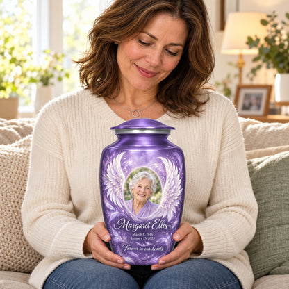 Seated person holding the purple adult angel wings urn on their lap.