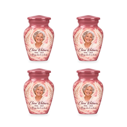 Four matching pink angel wings keepsake urns with sample photo and inscription.