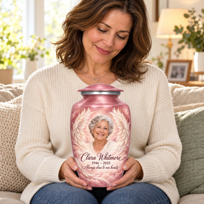 Seated person holding the pink adult angel wings urn on their lap.