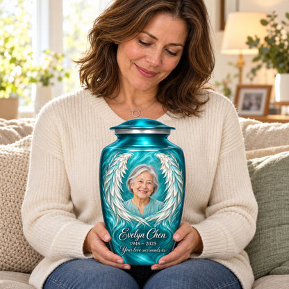 Seated person holding the blue adult angel wings urn on their lap.