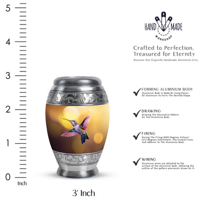 Sunrise Gold Hummingbird Cremation Urn lifestyle display on memorial shelf - ornate monarch-style hummingbird relief on brushed aluminum - mini keepsake memorial for portion of cremation ashes