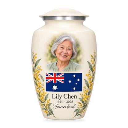 Ivory adult Ivory Wattle Remembrance urn with a fictional portrait above an Australian flag and watercolor golden wattle at the lower sides on white.