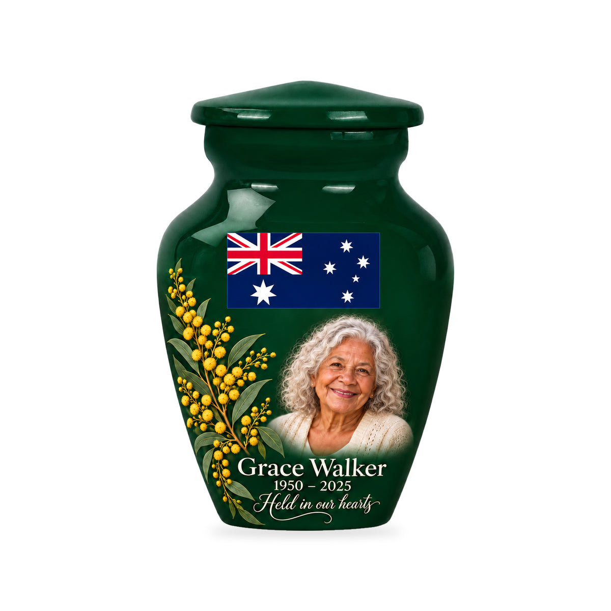 One emerald green ringless 3-inch keepsake urn with an upper Australian flag, golden wattle at lower left and a fictional portrait at lower center-right on white.