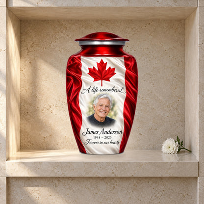 Red adult urn with Maple Silk Tribute Canadian flag artwork displayed in a columbarium niche.
