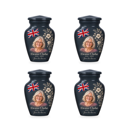 Four matching slate gray ringless keepsake urns with diagonally draped Union Jack and printed botanical linework and fictional sample personalization.