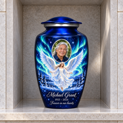 Blue adult urn with a floating angel, aurora sky, snowy trees and an oval sample portrait frame, displayed in a columbarium niche.