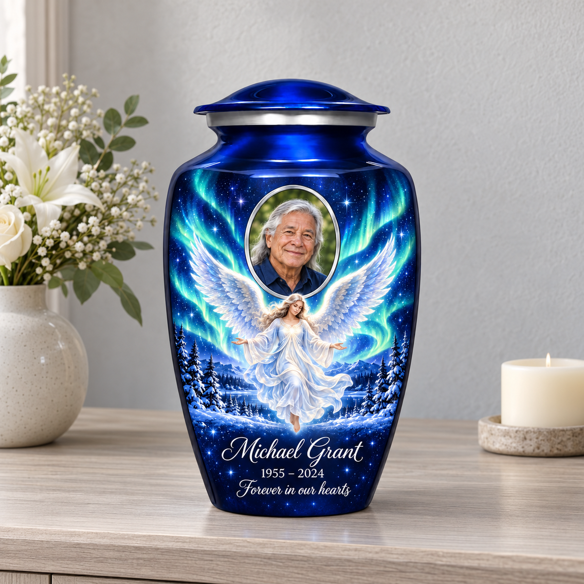 Blue adult urn with a floating angel, aurora sky, snowy trees and an oval sample portrait frame, displayed on a memorial console.