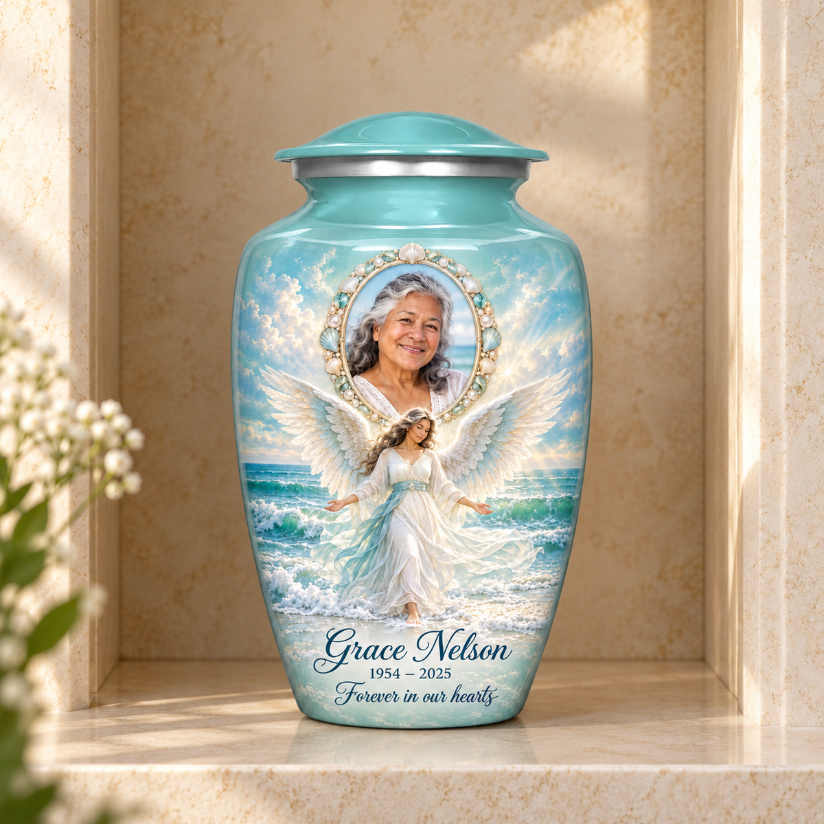 Blue adult urn with an ocean angel among waves and a shell style oval sample portrait frame, displayed in a columbarium niche.